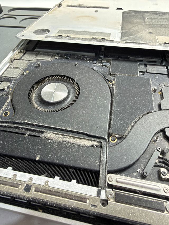 Interior de un MacBook con polvo acumulado en el ventilador